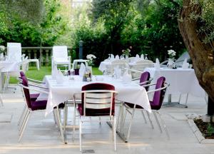 a group of tables with white tables and chairs at Hotel Sanja former Oliva in Budva