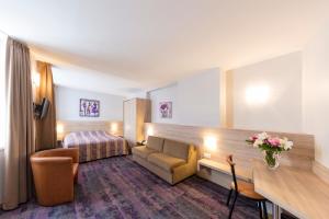 una camera d'albergo con divano e letto di Hôtel Vendôme a Strasburgo