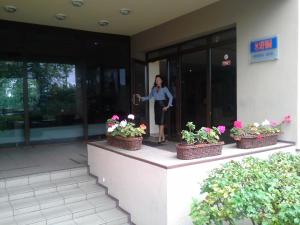 a woman standing outside of a building with flowers at Sky High Hotel Airport 200 meters from the terminal in Riga