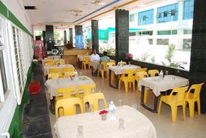 an empty restaurant with tables and yellow chairs at Hotel Utsav in Shirdi