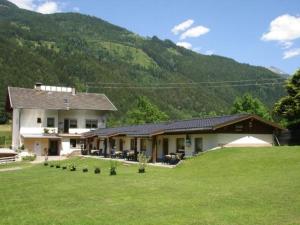 a large house in a field with a mountain at Ferienwohnung Fam. Bidner in Flattach