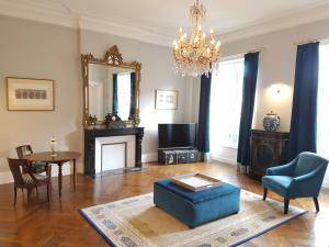 Sala de estar con silla, mesa y espejo en Le Tardif, Noble Guesthouse, en Bayeux