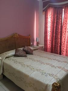 a bedroom with a bed and a window with red curtains at Ix Xaluppa J6 Apartment in Għajnsielem