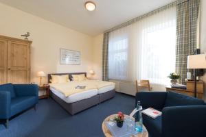 ein Hotelzimmer mit einem Bett und zwei Stühlen und einem Tisch in der Unterkunft Atlantic Hotel Garni in Wangerooge
