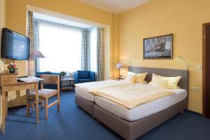 ein Hotelzimmer mit einem Bett, einem Schreibtisch und einem Fernseher in der Unterkunft Atlantic Hotel Garni in Wangerooge