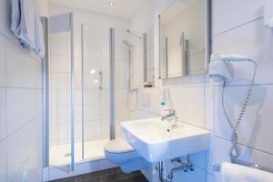 ein Badezimmer mit Waschbecken, Toilette und Dusche in der Unterkunft Atlantic Hotel Garni in Wangerooge