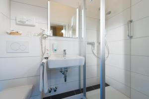 ein weißes Badezimmer mit Waschbecken und Dusche in der Unterkunft Atlantic Hotel Garni in Wangerooge