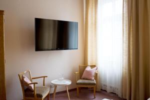 Zimmer mit 2 Stühlen, einem Tisch und einem TV an der Wand in der Unterkunft Fink Low Budget Rooms in Wien