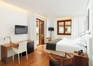 a hotel room with a bed and a desk and a television at Iberostar Heritage Grand Mencey in Santa Cruz de Tenerife