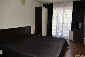 1 dormitorio con cama negra y ventana en Pensiunea Pinul Negru en Băile Herculane