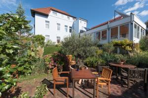 eine Terrasse mit Tischen und Stühlen und ein Gebäude in der Unterkunft Atlantic Hotel Garni in Wangerooge
