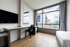 a hotel room with a desk and a large window at Z Sleep Hotel in Hat Yai
