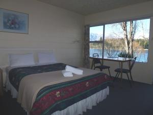 1 dormitorio con cama, mesa y ventana en Lakeside Motel, en Queenstown
