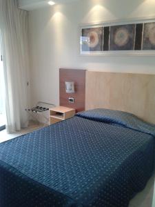 a bedroom with a bed with a blue comforter at Hotel Albatros in Terracina