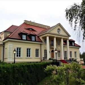 duży biały dom z czerwonym dachem w obiekcie Dwor Osieczek w mieście Pniewy