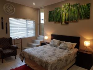 a bedroom with a bed and two chairs and a clock at Studio on Bourdeaux in Panorama