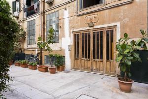 a building with a large wooden door and potted plants at Sofia's House in Palermo
