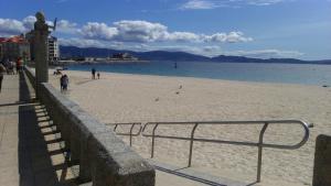 plaża z ludźmi chodzącymi po piasku i wodzie w obiekcie Apartamento Gallego VUT-PO-02510 w mieście Sanxenxo