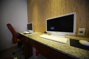 a computer monitor on a desk with a keyboard and mouse at First Hotel in Guri