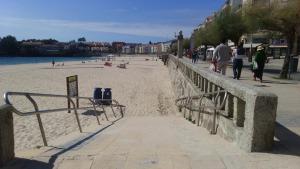 a sandy beach with people walking on the beach at Apartamento Gallego VUT-PO-02510 in Sanxenxo