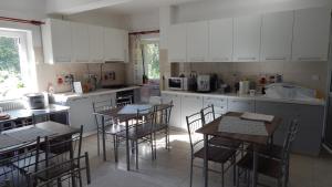 a kitchen with white cabinets and tables and chairs at Olt-Part Vendégház in Băile Tuşnad