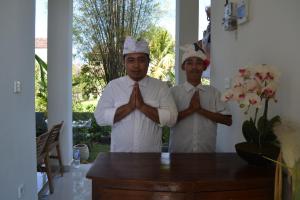 two men in chefsuitsuits praying in front of a table at Master Homestay in Amed