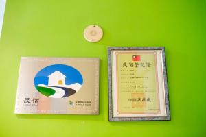two certificates on a green wall with a clock at New Fox Guest House in Zhuangwei