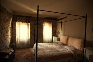 - une chambre avec un lit à baldaquin et 2 fenêtres dans l'établissement Castello di Brandola, à Polinago
