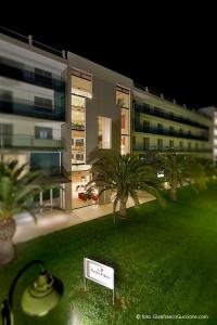 a building with palm trees and a sign in the grass at Eureka Palace Hotel Spa Resort in Cassibile