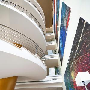 a spiral staircase in a room with paintings at Eureka Palace Hotel Spa Resort in Cassibile