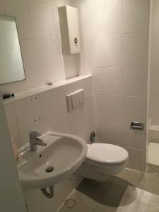 a white bathroom with a toilet and a sink at Kölner Pension in Cologne