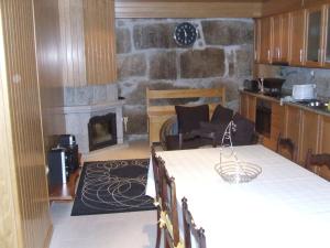 a kitchen with a stone fireplace and a table and chairs at Casa da Bôcha in Cativelos