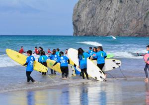 a group of people walking on the beach with surfboards at Watsay Surf House in Santoña