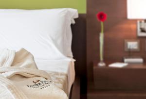 a bed with a white pillow and a red flower on a table at Eureka Palace Hotel Spa Resort in Cassibile