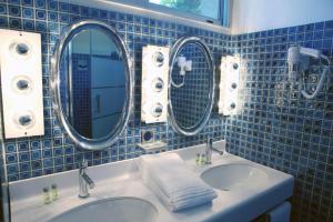 a blue tiled bathroom with two sinks and two mirrors at Mas de L'Ermitage in Lattes