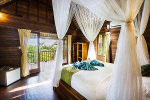 1 dormitorio con 1 cama con cortinas y balcón en Laguna Reef Huts, en Nusa Lembongan