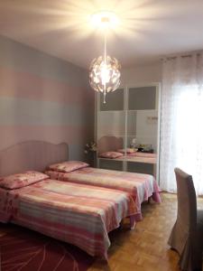 een slaapkamer met 2 bedden en een kroonluchter bij Happy Holidays Welcome in Trieste