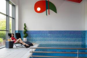 Talbot Hotel Clonmel في كلونيمل: امرأة جالسة على كرسي بجوار حمام السباحة