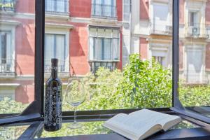 - une bouteille de vin et un livre sur une table avec une fenêtre dans l'établissement LEEWAYS LOFT in FUENCARRAL, à Madrid