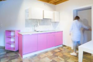 a woman standing in a kitchen with a pink cabinet at Residence Vis à Vis in Rasùn di Sotto