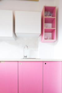 een keuken met roze kasten en een wastafel bij Residence Vis à Vis in Rasùn di Sotto