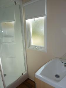 baño con ducha, lavabo y ventana en Camping du RIED en Boofzheim