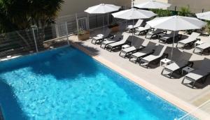 a swimming pool with lounge chairs and umbrellas at Ibis Budget Hyères in Hyères