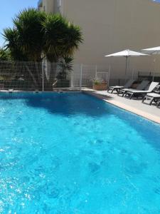 a large blue swimming pool with chairs and umbrellas at Ibis Budget Hyères in Hyères