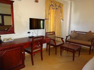 ein Wohnzimmer mit einem Schreibtisch, Stühlen und einem TV in der Unterkunft Pagoda Heritage Inn in Alappuzha