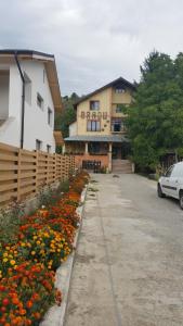 a building with a bunch of flowers next to a driveway at Pensiunea BRADU in Piatra Neamţ