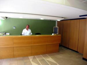 een man die achter een balie in een kantoor staat bij Diana Hotel in Chios