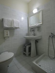 La salle de bains blanche est pourvue d'un lavabo et de toilettes. dans l'établissement Diana Hotel, à Chios