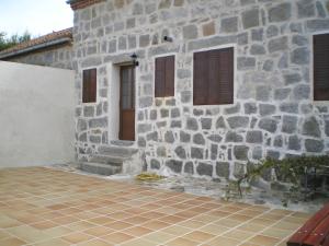 a stone building with a door and windows and a patio at Casa Luz in Ávila