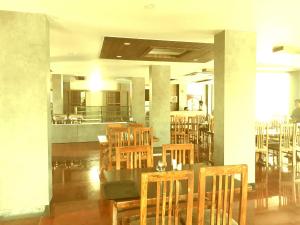a restaurant with wooden chairs and a table and a kitchen at Hotel Abhilasha in Giriak